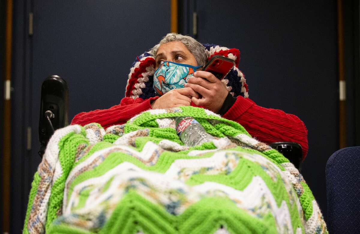 Maria Laboy talks to people on the phone while staying at Lakewood Church on Feb. 16. Laboy came to the warm center on Monday night due to lost of power at her home.