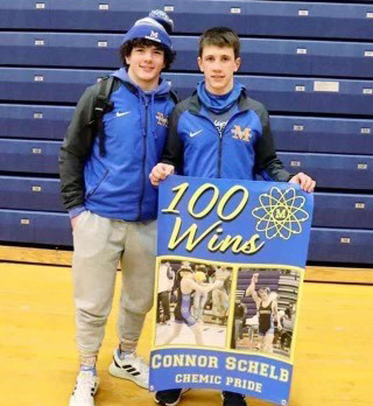 Midland High's Connor Schelb poses with a banner commemorating his 100th career wrestling victory at Saturday's Chippwa Hills quad.