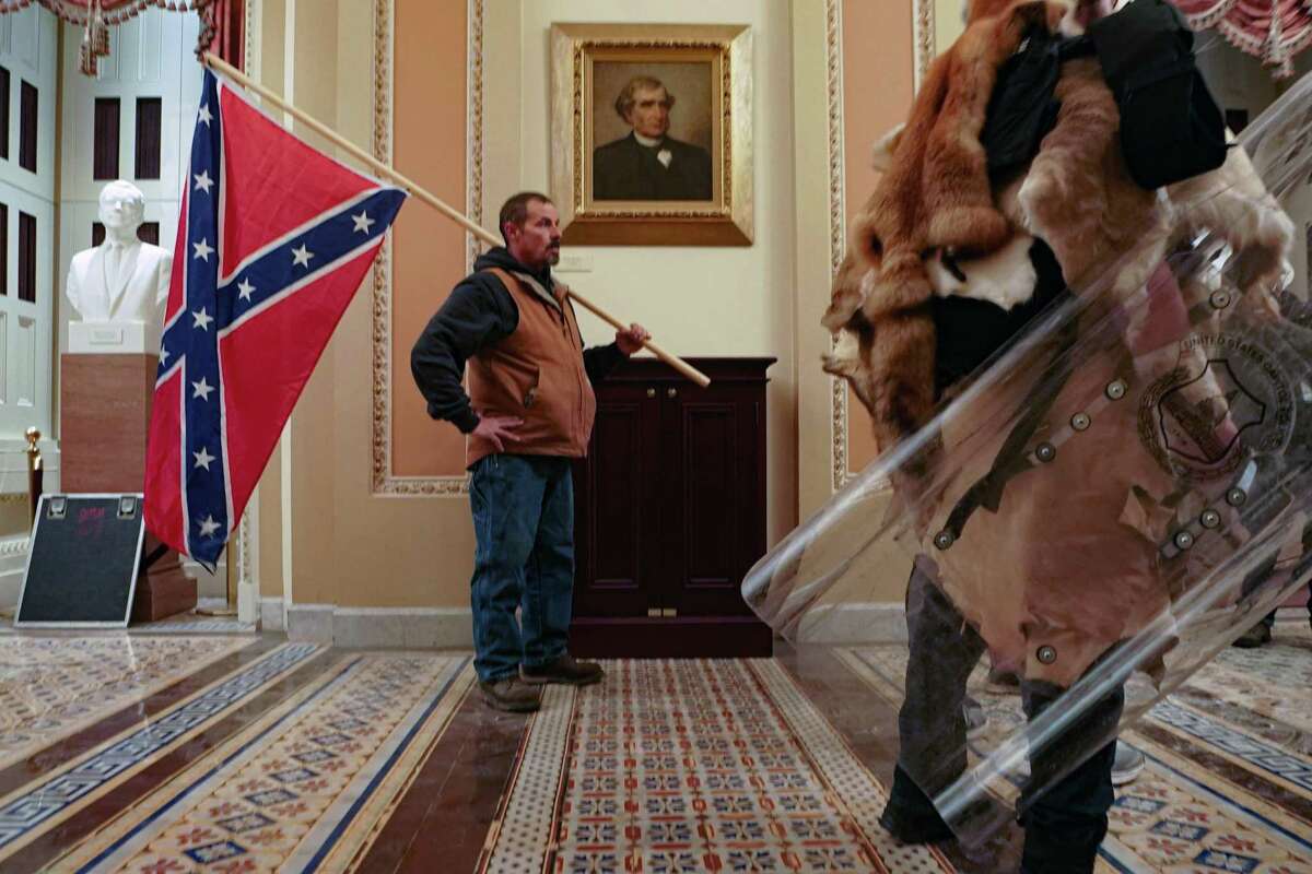 FILE PHOTO A supporter of President Donald Trump carries a Confederate battle flag inside the Capitol building in Washington, as a mob of his supporters protest the presidential election results, on Wednesday, Jan. 6, 2021. Historians said it was unnerving to see a man carry the flag inside the Capitol, something not even Confederate soldiers were able to do during the Civil War. (Erin Schaff/The New York Times)