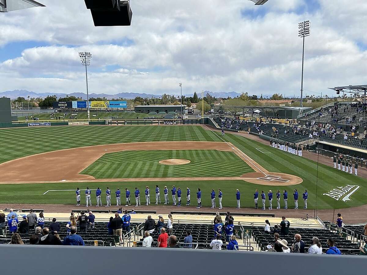 The Oakland A's and Los Angeles Dodgers line up for the national anthem before their Cactus League opener at Hohokam Stadium in Mesa, Ariz., on February 28, 2021