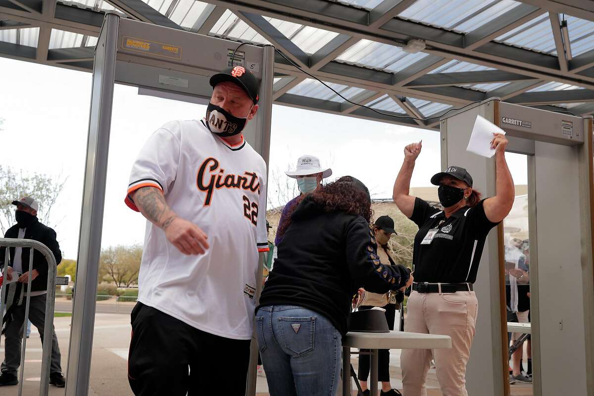 Richard Hutchinson, left, and Tammie Farris, center, get a cheer from a security worker as they enter the stadium before the San Francisco Giants played the Los Angeles Angels at Scottsdale Stadium in Scottsdale, Ariz., on Sunday, February 28, 2021.