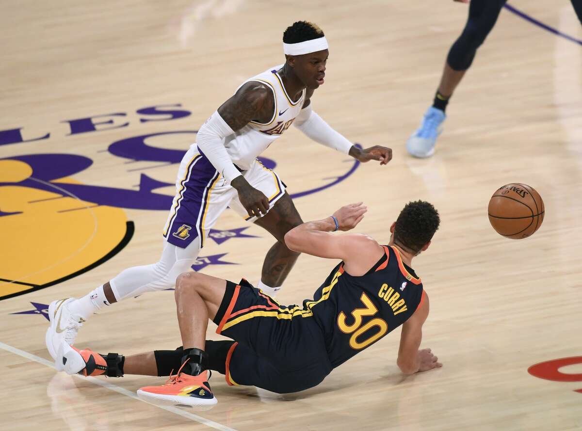 Stephen Curry of the Golden State Warriors falls while guarded by Dennis Schroder of the Los Angeles Lakers on February 28, 2021.