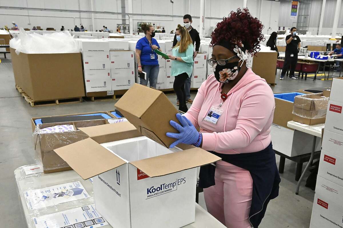 一名工人将新批准的强生COVID-19疫苗包装到冷却器中，以便从肯塔基州谢博德斯维尔的麦克森公司分销设施运输。