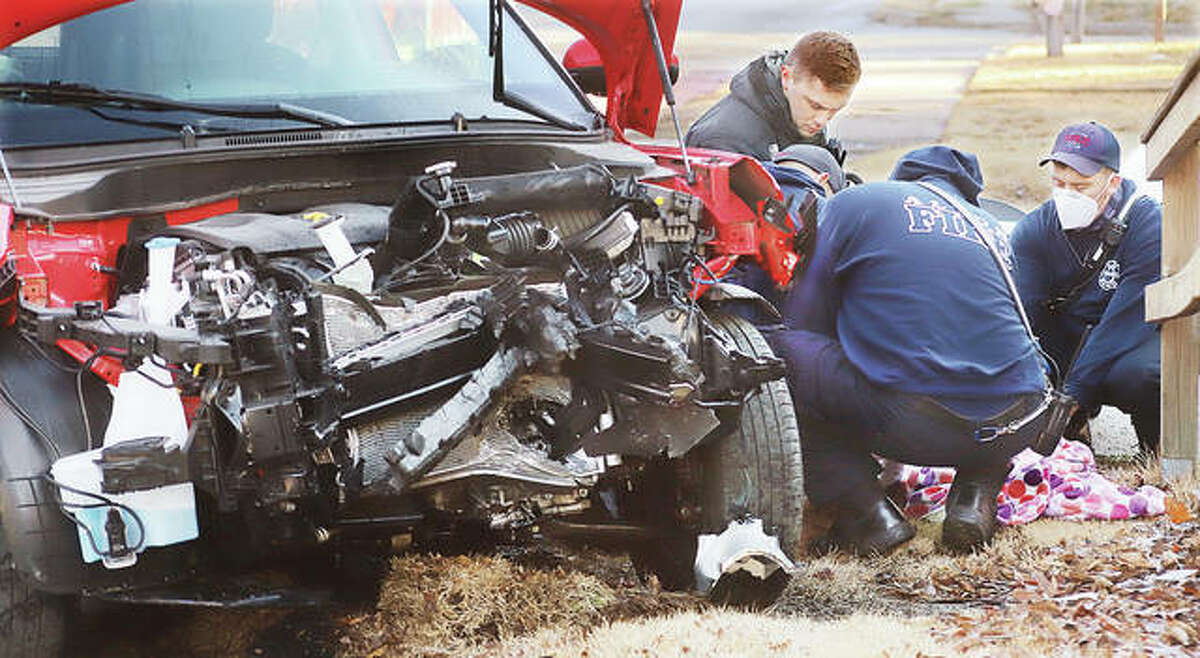 Alton firefighters huddle around the injured female driver of a Kia Soul early Monday morning following a head-on crash with a Ford Taurus in the 1100 block of Brown Street in Alton. The crash occured shortly after 7:30am with one of the cars ending up on a sidewalk students walk to school on. Both drivers were sent to area hospitals.