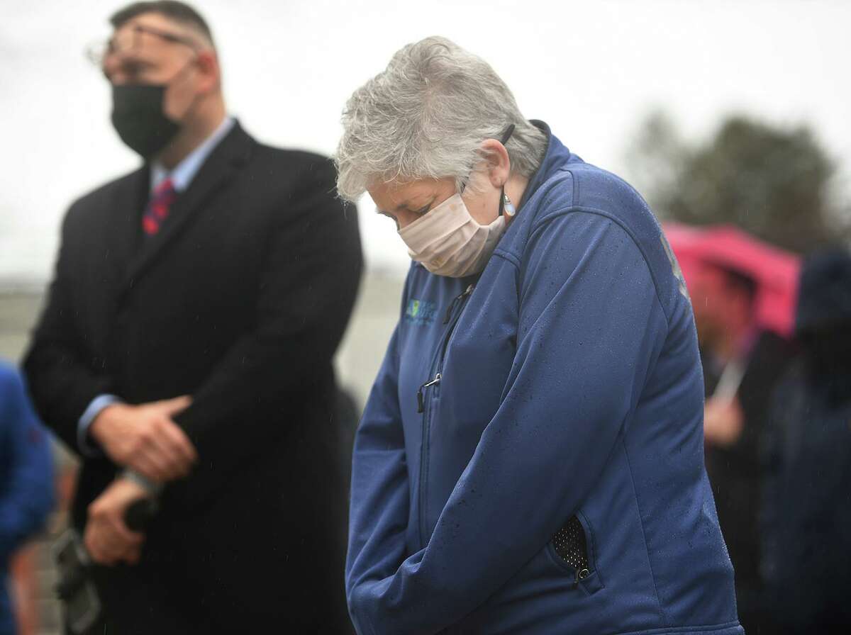 Stratford Health Director Andrea Boissevain bows her head during a remembrance vigil for COVID-19 victims and survivors on the one year anniversary of the first U.S. death from the virus outside City Hall in Stratford, Conn. on Monday, March 01, 2021.
