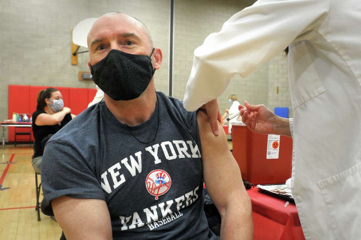 Chris Varcoe, a teacher from Roger Ludlowe Middle School, in Fairfield, receives a COVID-19 vaccination at the Bigelow Center clinic in Fairfield, Conn. March 1, 2021.