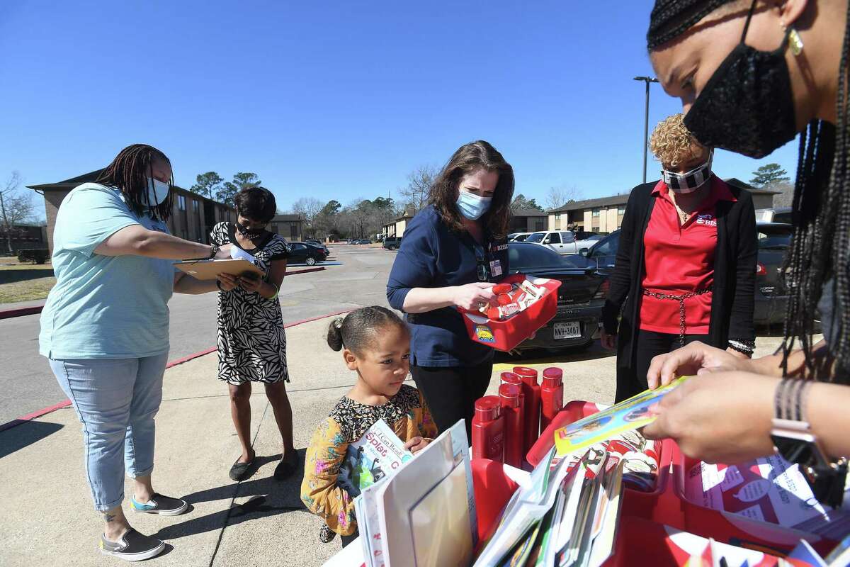 Veronica Redmon helps as Josiah Brown steps up to select books during the Beaumont ISD Parent Involvement Committee's caravan Tuesday. Committee members and BISD staff joined in the event to bring books, snacks and toiletries to area students during this week's virtual learning. Photo made Tuesday, February 23, 2021 Kim Brent/The Enterprise
