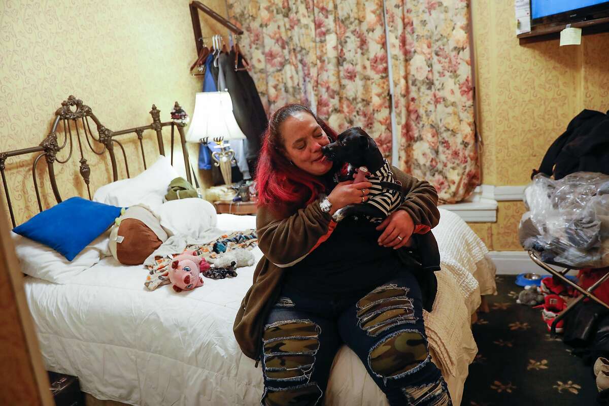 Chucky Torres embraces her dog, Yoda, in her hotel room in the Tenderloin. Chucky was previously homeless and hoping to get permanent housing.