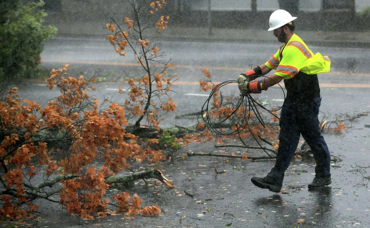 A file photo of a utility worker clearing wires as a fallen tree limb blocks a portion of Main Avenue in Norwalk, Conn.