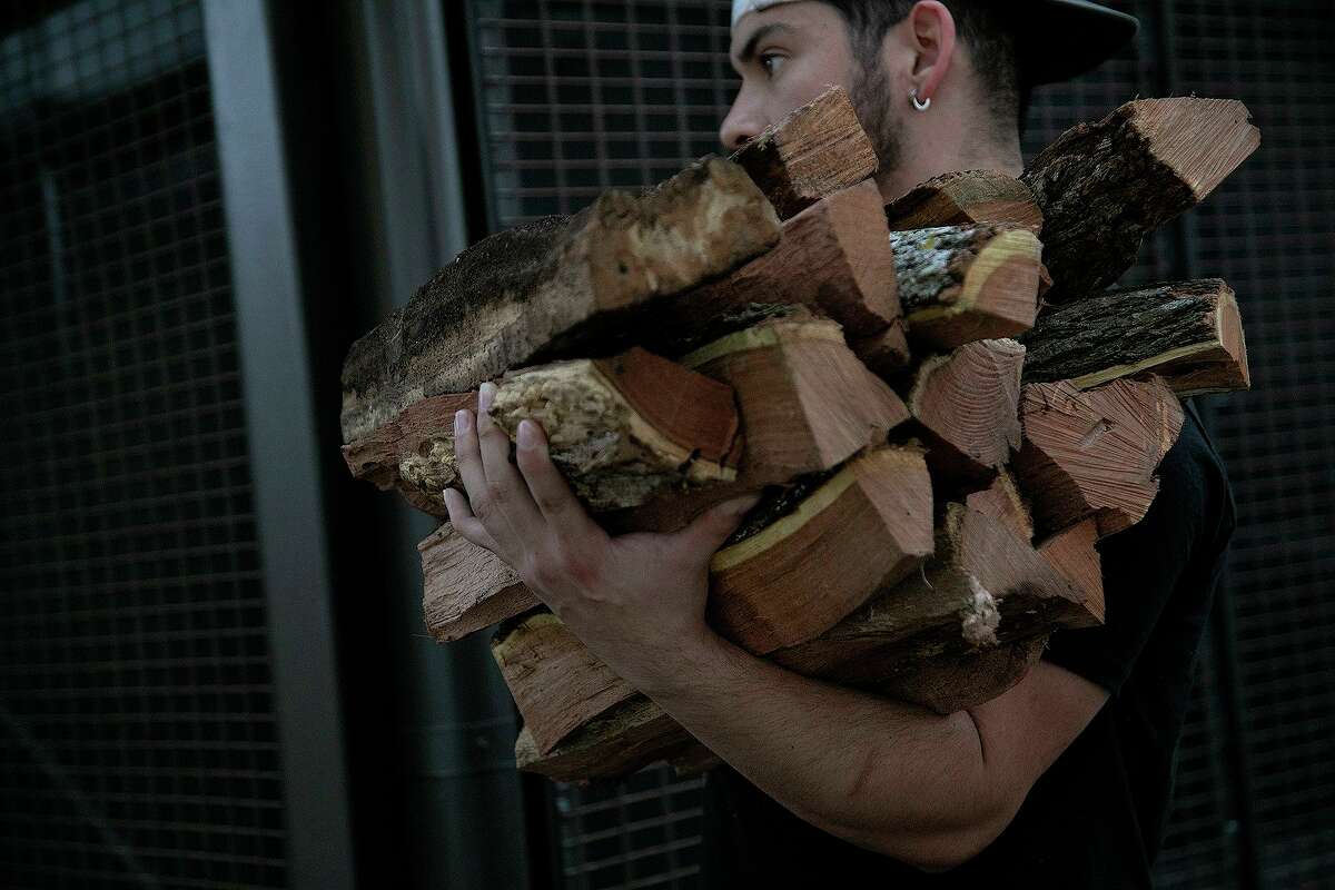 Just after the polar vortex, Gilbert Cantu carries oak wood for the barbecue pits at Pinkerton's Barbecue in downtown San Antonio. The Houston location’s wood supplies were dicey during the storm.