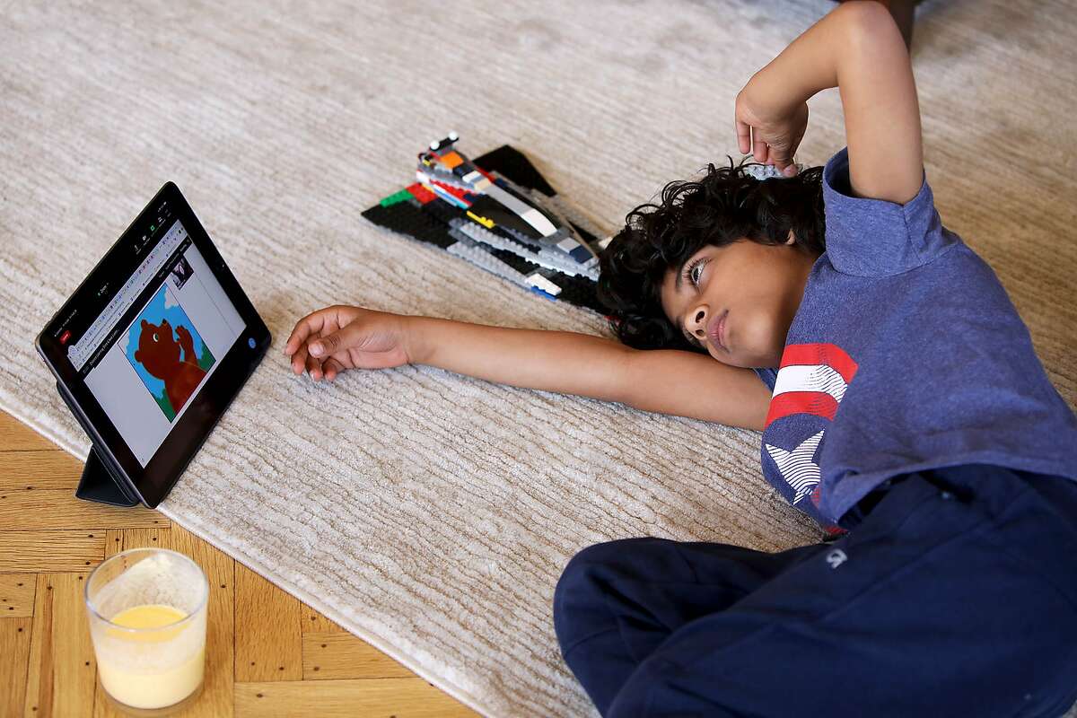 Jeevan Guha, 6, relaxes on the living room floor as he attends his Zoom class on Friday, January 26, 2021, in San Francisco.