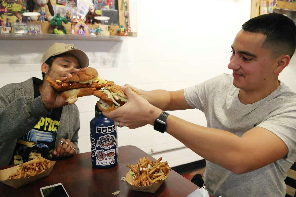 Isaac Sarabia, left, and his brother Dominick Mata toast with their sandwiches while eating lunch at Smack’s Chicken Shack Monday.