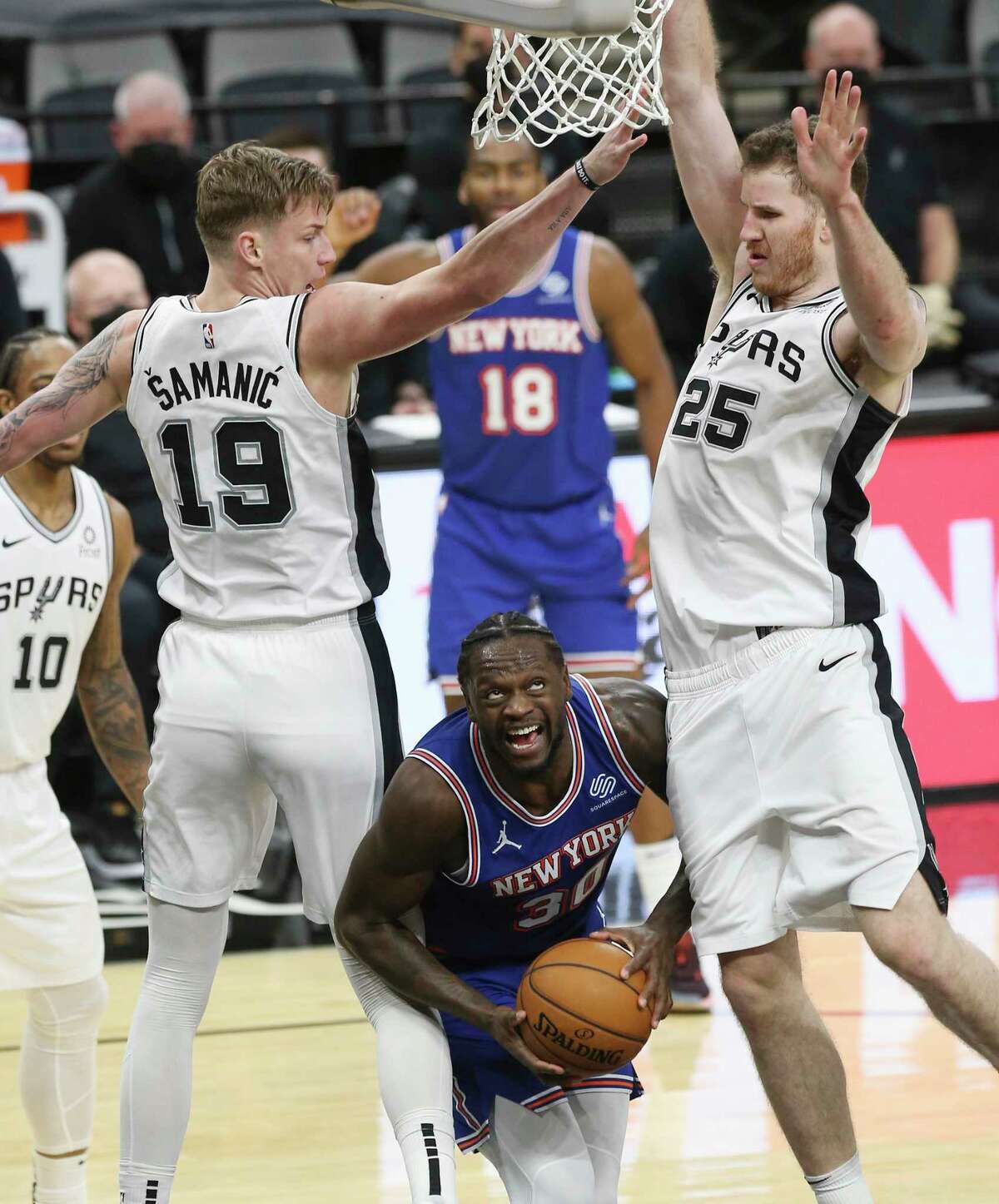Spurs' Luka Samanic (19) and Jakob Poeltl (25) hover over New York Knicks' Julius Randle (30) at the AT&T Center on Tuesday, Mar. 2, 2021.