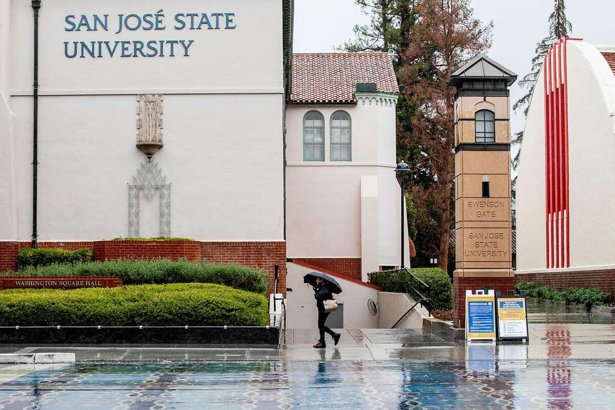 A person walks with an umbrella past San Jose State’s campus as rain falls in San Jose in January.