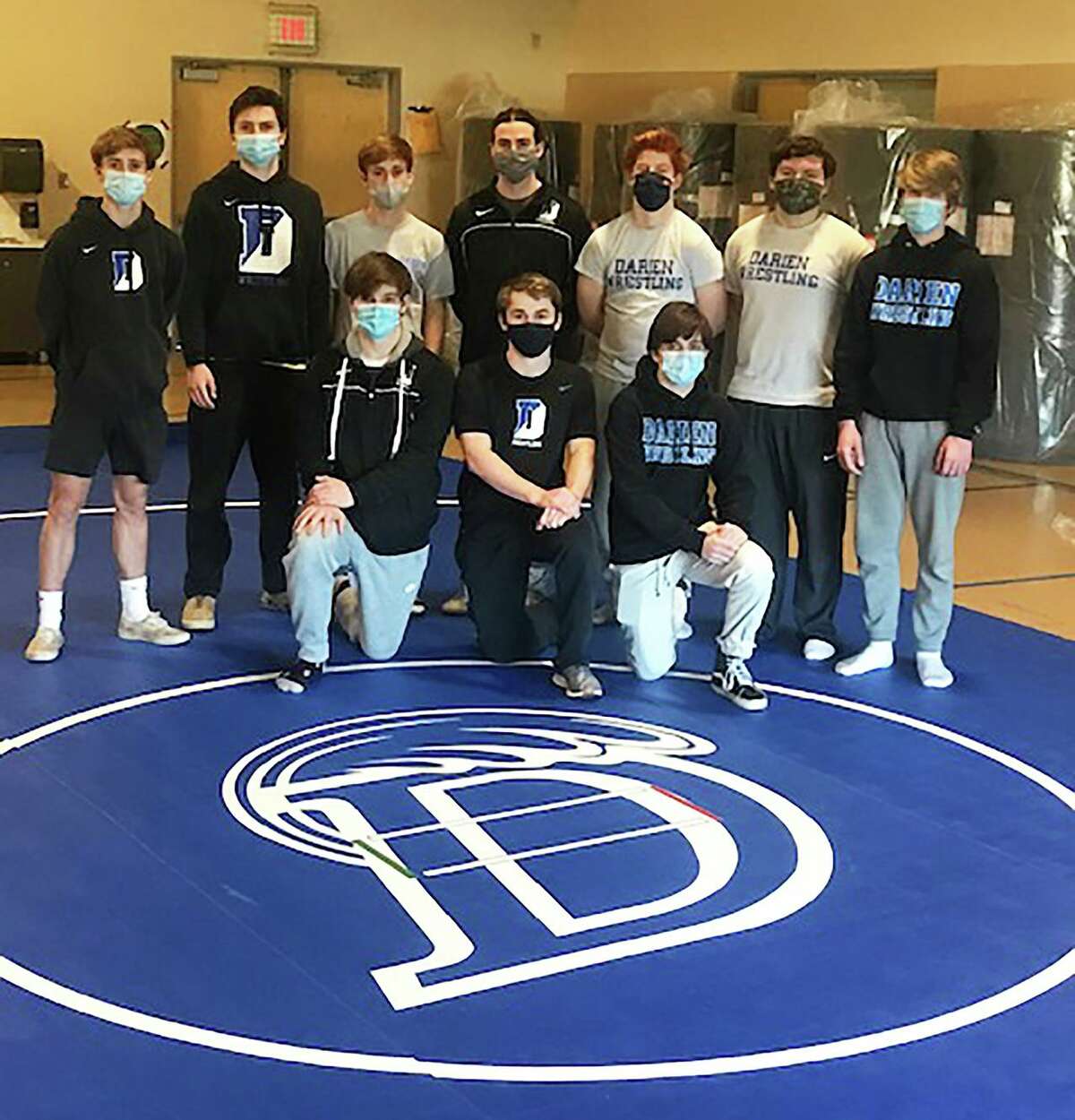 The Darien wrestling team poses with a new mat provided by the Blue Wave Booster Club.