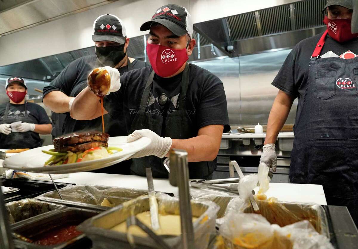 Eduardo Francisco garnishes a plate as he and others all wear masks as they work at The Union Kitchen in Katy.