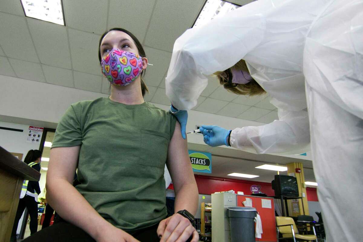 Danbury teacher Lauren Brown gets her Moderna COVID-19 vaccination at a vaccine clinic at Rogers Park Middle School in Danbury, Conn., on Saturday Mar. 6, 2021. Administering the shot is Danbury Hospital X-ray supervisor Lori Mazzucco. Over 900 teachers and staff received the Moderna vaccine during the two-day clinic.