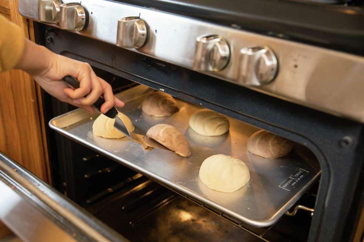 Agueda Ulloa checks on some conchas, a Mexican sweet bread, she was baking in her home oven in Union City, Calif. on March 3, 2021. She started her home business, named Cafe de la Olla, using a family recipe that she slightly tweaked.