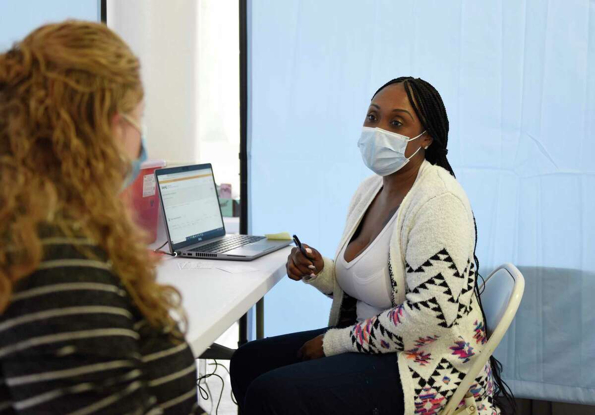 Denisha Russell, LPN, consults with a patient before administering the COVID-19 vaccine at the Family Centers vaccination clinic at the Eastern Greenwich Civic Center in Old Greenwich, Conn. Monday, March 1, 2021. March 1 marked a massive expansion of vaccine eligibility as all Connecticut residents age 55 and up are now eligibile.