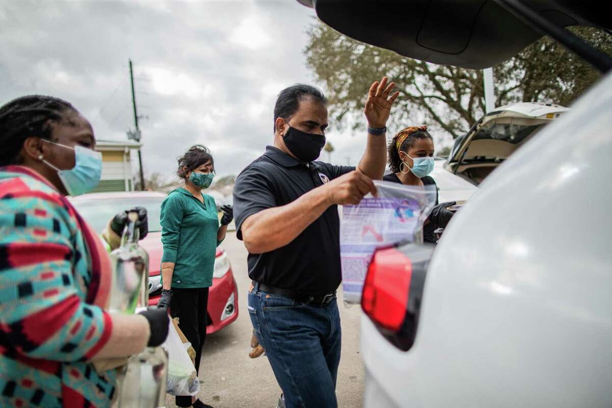 Fort Bend County Judge KP George places a bag of personal protective equipment to the vehicle of someone who came to a food distribution event at the North Richmond Neighborhood Resource Center, Wednesday, Feb. 24, 2021, in Richmond.