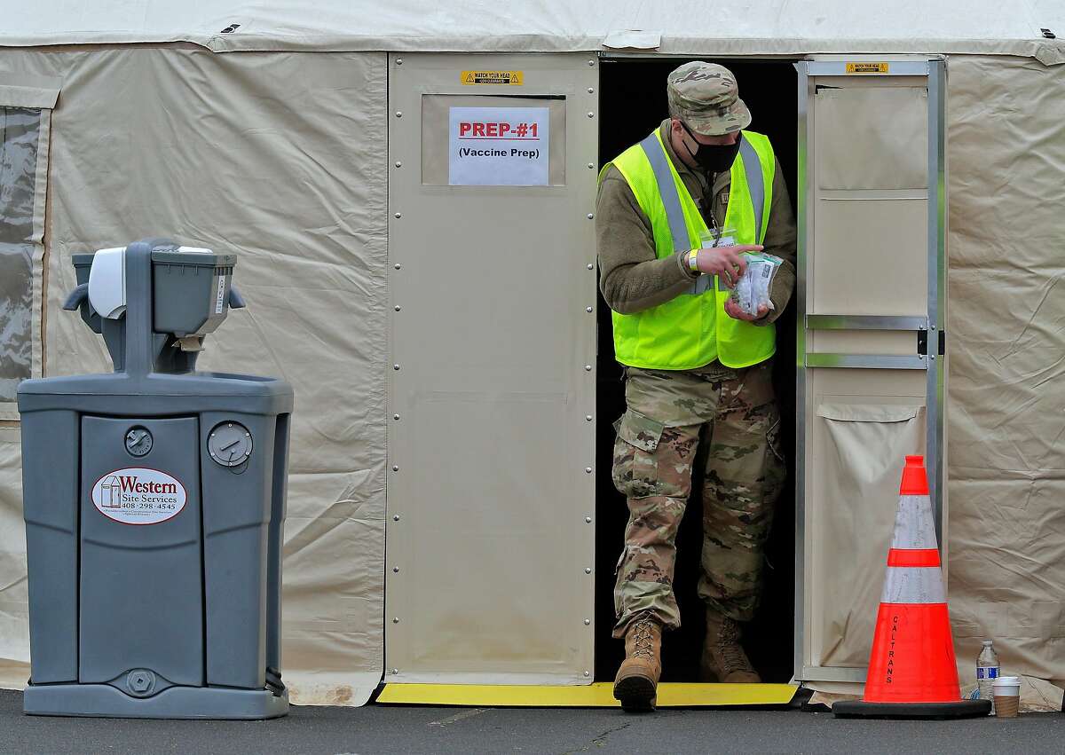 A California National Guard member carries prepped Pfizer COVID-19 vaccines to the healthcare workers as vaccinations were administered to the public for the first day of mass vaccinations at the Oakland Coliseum in Oakland, Calif., on Tuesday, February 16, 2021.