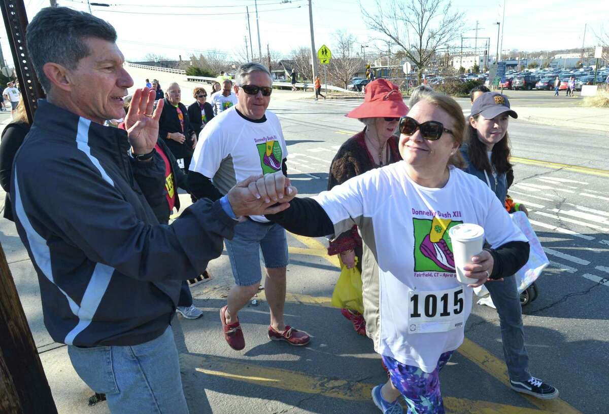 Family friend and starter Marty Schaivone high fives walkers as they start of The Donnelly Dash Sunday April 9, 2017 at Tomlinson Middle School in Fairfield Conn.The 3. 5 mile run or walk event was founded to celebrate the lives of Tim & Kim Donnelly, tragically taken on Feb 2, 2005 ( murdered in their downtown jewelry store). The run and walk benefits local charities as beneficiaries and partners, the Greater Bridgeport Youth Orchestras, Fairfield Police Explorers Post, and the Fairfield Police Union Scholarship Fund.