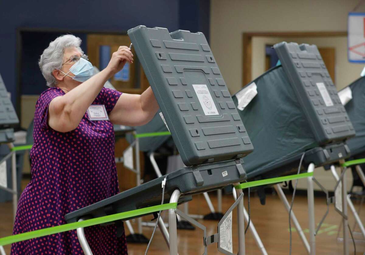 Kathy Trahan wears a facemask as she sets up voting stations before the polls open at the South Montgomery County Community Center, Thursday, July 2, 2020, in The Woodlands. Election officials have implemented several safety and sanitization features to protect voters and polling location volunteers from the coronavirus.