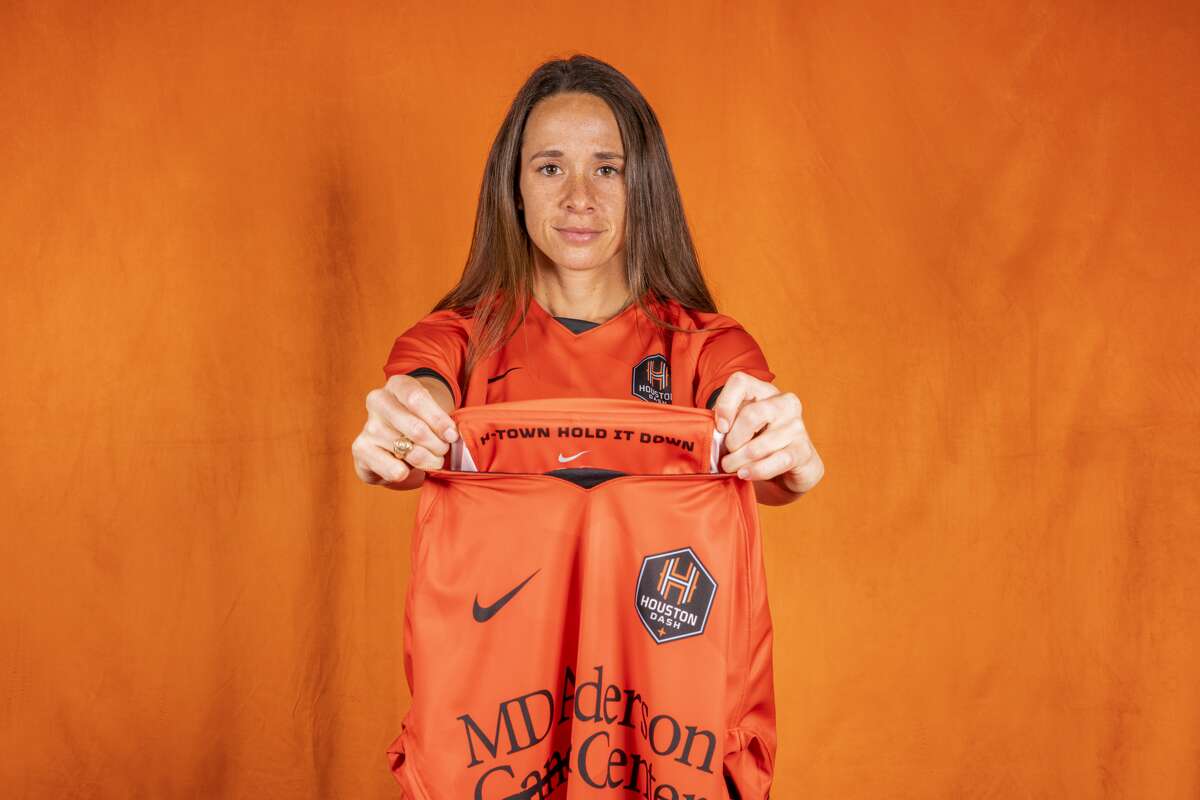 Shea Groom from the Houston Dash shows off the new jerseys for the 2021 season, including the words inside the neckline.