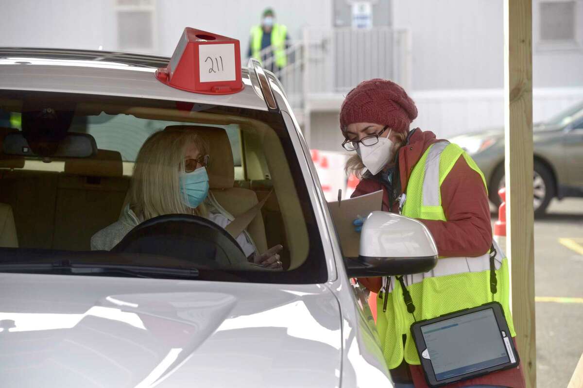 Loretta Foley, of Shelton,, gives her information to Denise Noto, an RN with Danbury Hospital, at Danbury's first mass COVID-19 vaccination site opened Thursday at the Danbury Fair mall. The Community Health Center, Inc site will utilize six car lanes to serve 600 appointments a day. March 4, 2021, in Danbury, Conn.