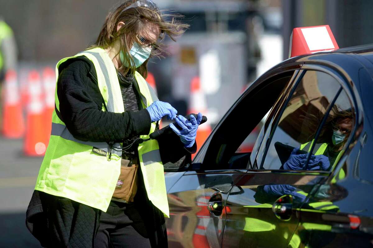 Elizabeth Katzing, RN, takes information from a person waiting in line at Danbury's first mass COVID-19 vaccination site which opened Thursday at the Danbury Fair mall. The Community Health Center, Inc site will utilize six car lanes to serve 600 appointments a day. March 4, 2021, in Danbury, Conn.