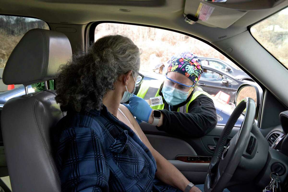 Ashley Matos, an RN with Danbury Hospital, administers a vaccination to Tania Lariccia, of Danbury, at Danbury's first mass COVID-19 vaccination site. The Community Health Center, Inc site will utilize six car lanes to serve 600 appointments a day at the Danbury Fair mall. Thursday, March 4, 2021, in Danbury, Conn.