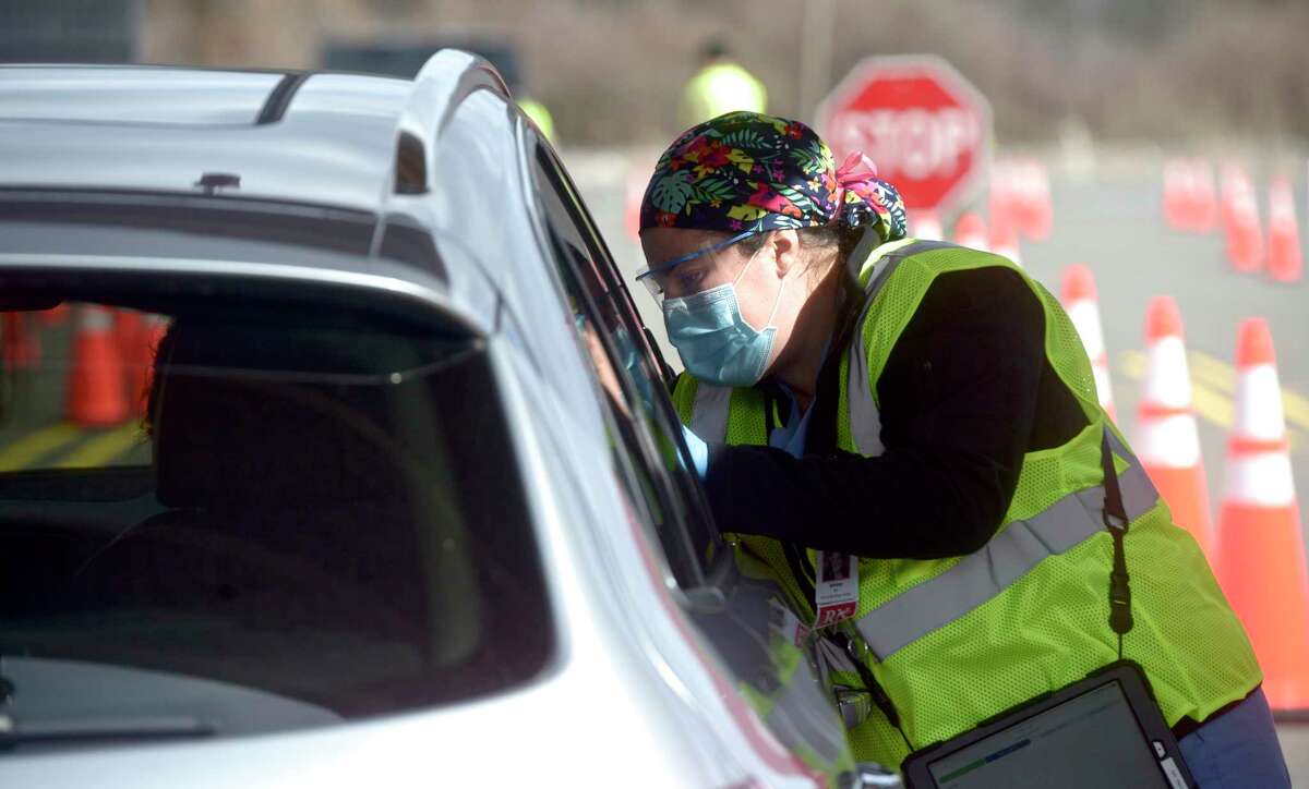 Ashley Matos, an RN with Danbury Hospital, administers a vaccination at Danbury's first mass COVID-19 vaccination site. The Community Health Center, Inc site will utilize six car lanes to serve 600 appointments a day at the Danbury Fair mall. Thursday, March 4, 2021, in Danbury, Conn.