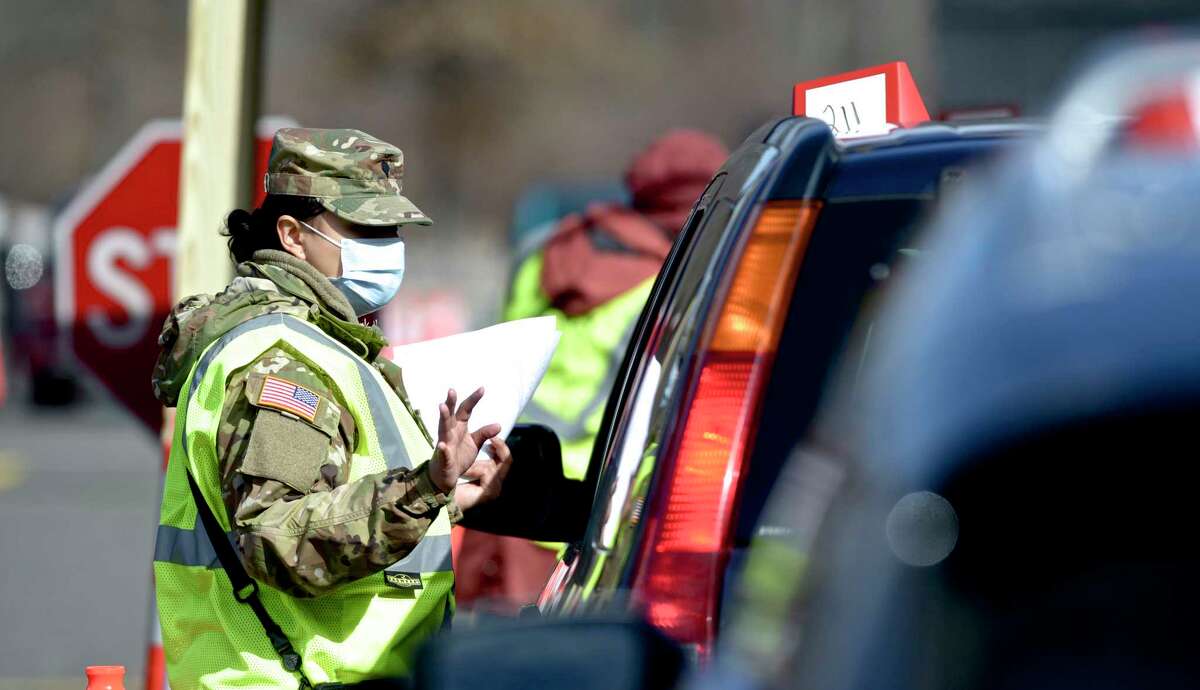 Specialist Samantha Pozo, of Danbury, a medic with the CT National Guard, takes information from a person waiting in line at Danbury's first mass COVID-19 vaccination site. The Community Health Center, Inc site will utilize six car lanes to serve 600 appointments a day at the Danbury Fair mall. Thursday, March 4, 2021, in Danbury, Conn.