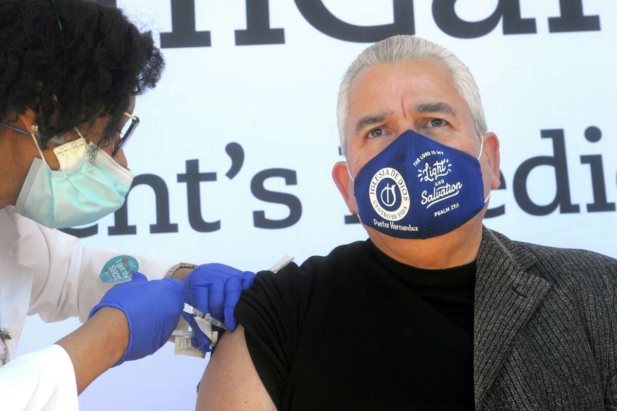 Nurse Marie St. Jean administers a COVID-19 vaccination to Bishop Hector Hernandez of Iglesias de Dios during a news conference in front of St. Vincent's Medical Center, in Bridgeport, Conn. Feb. 26, 2021. Nine black and Latino clergy members from various Bridgeport ministries received vaccinations at the Friday event.