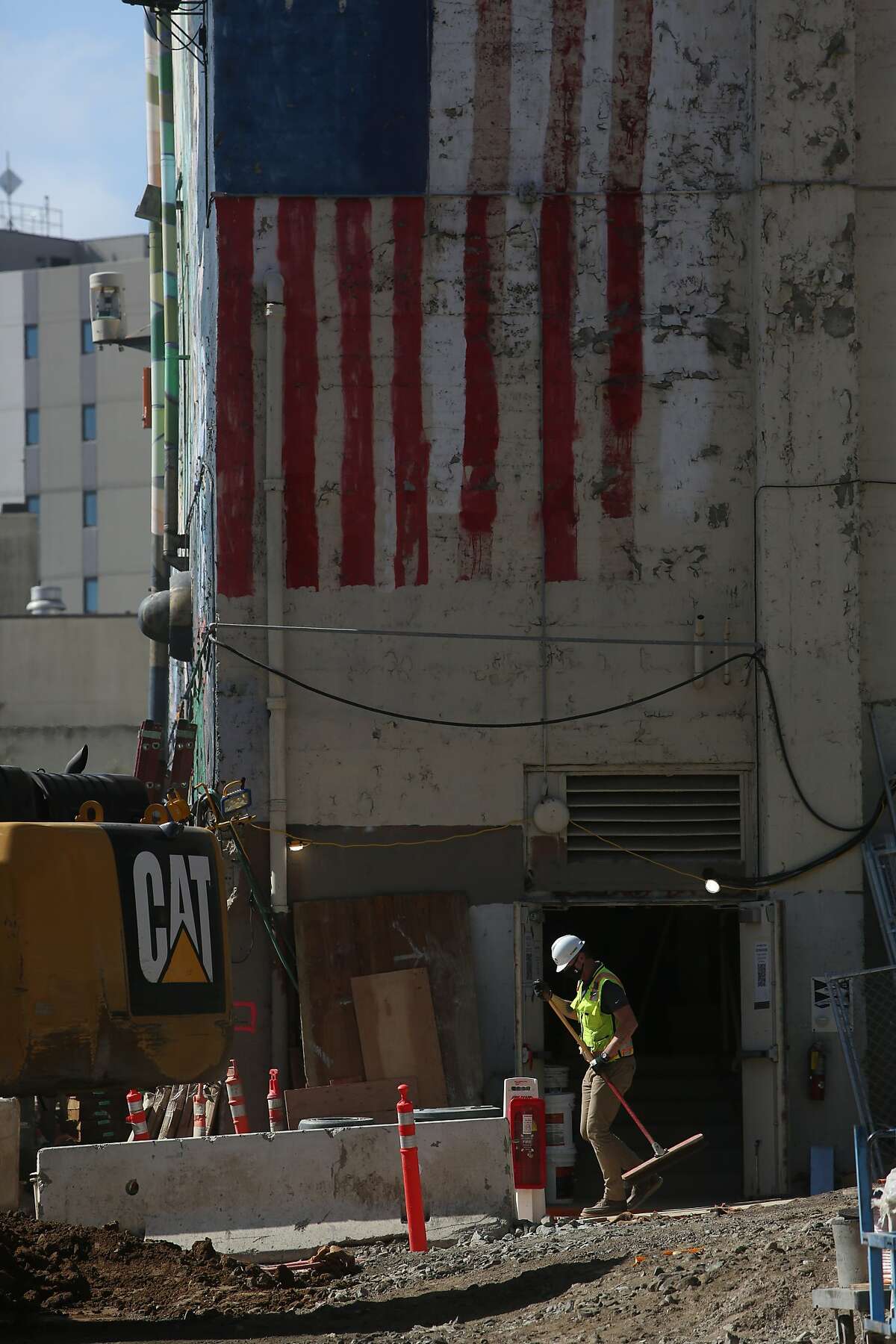 A worker sweeps outside the existing union hall at the site of the Plumbers and Pipefitters Local 38 project where 499 units of housing are being built in addition to the supportive housing complex at 53 Colton St.