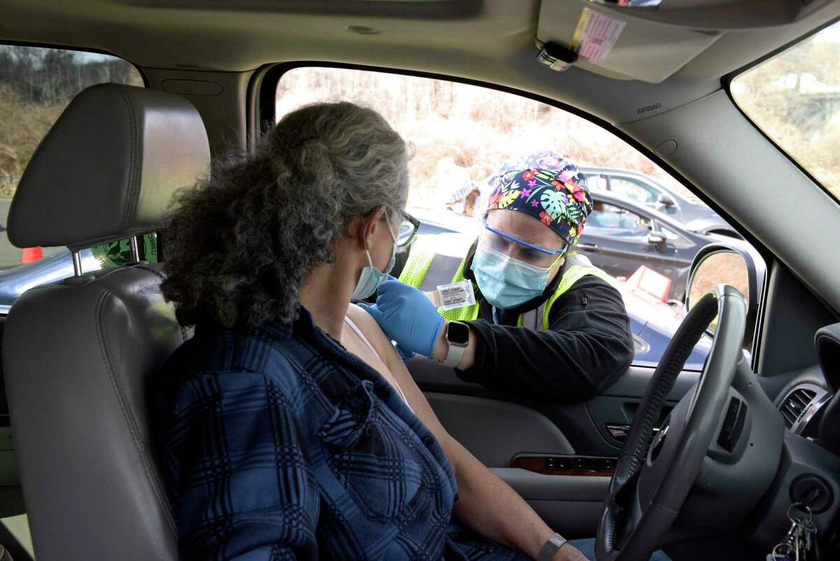 Ashley Matos, an RN with Danbury Hospital, administers a vaccination to Tania Lariccia, of Danbury, at Danbury's first mass COVID-19 vaccination site. The Community Health Center, Inc site will utilize six car lanes to serve 600 appointments a day at the Danbury Fair mall. Thursday, March 4, 2021, in Danbury, Conn.