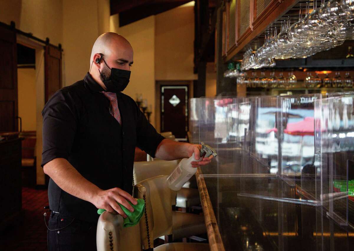 Arnaldo Richard's Picos Restaurant bartender Daniel Vázquez sanitizes the countertop after customers left Thursday, March 4, 2021, in Houston. Following Gov. Greg Abbott's order lifting the statewide mask mandate and other COVID-19 restrictions, many Houston restaurants like Picos have vowed to keep those measures in place. Now they're getting threats.