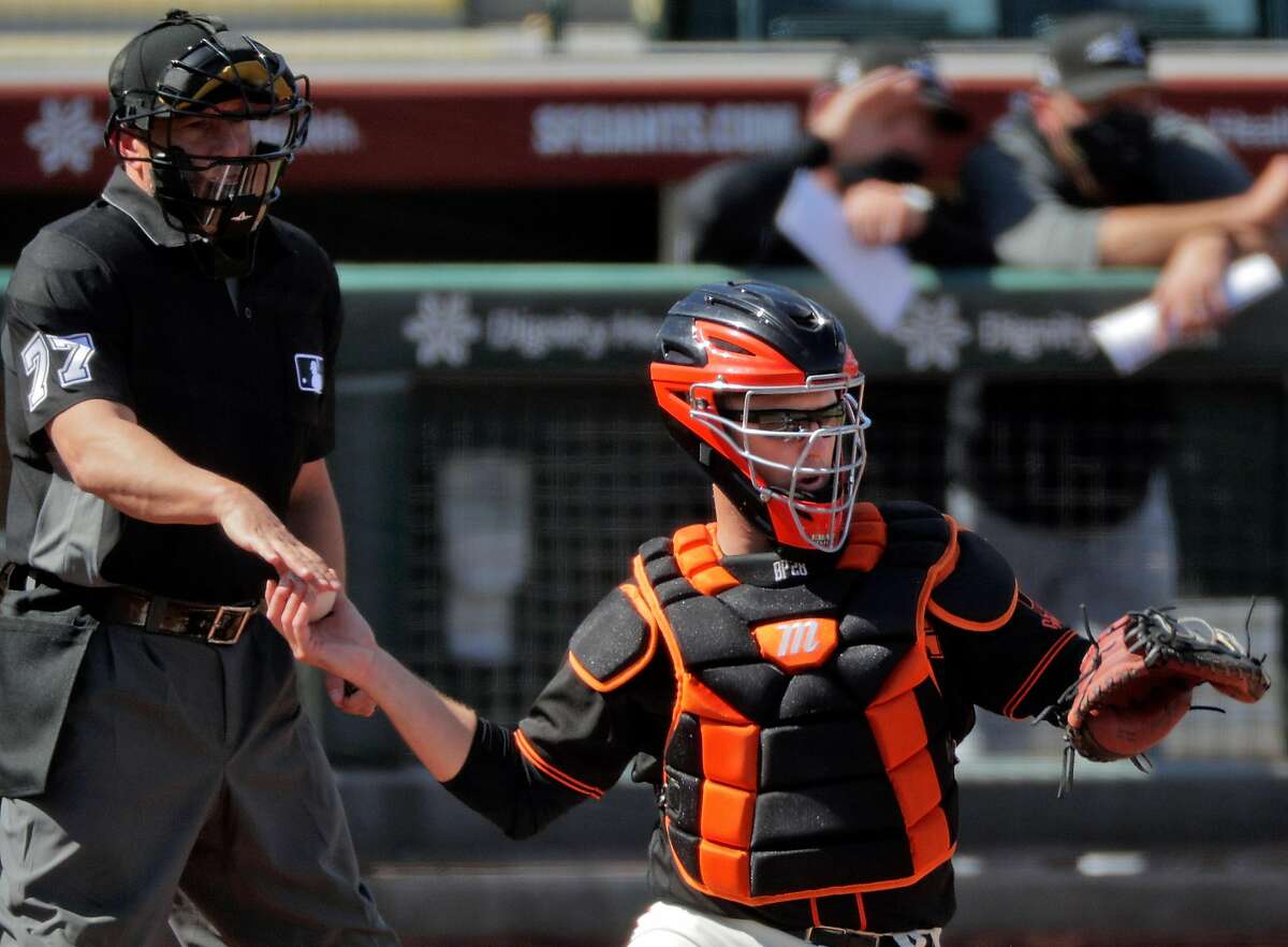 Buster Posey (28) gets a new ball from home plate umpire Jim Reynolds (77) in the second inning as the San Francisco Giants played the Chicago White Sox in a spring training game at Scottsdale Stadium in Scottsdale, Ariz., on Thursday, March 4, 2021.