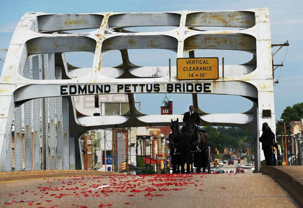 The body of Rep. John Lewis pauses at the top of the bridge for one minute while making the final crossing over the Edmund Pettus Bridge, site of the historic 1965 voting rights marches, while family members at right look on Sunday, July 26, 2020 in Selma, Ala.