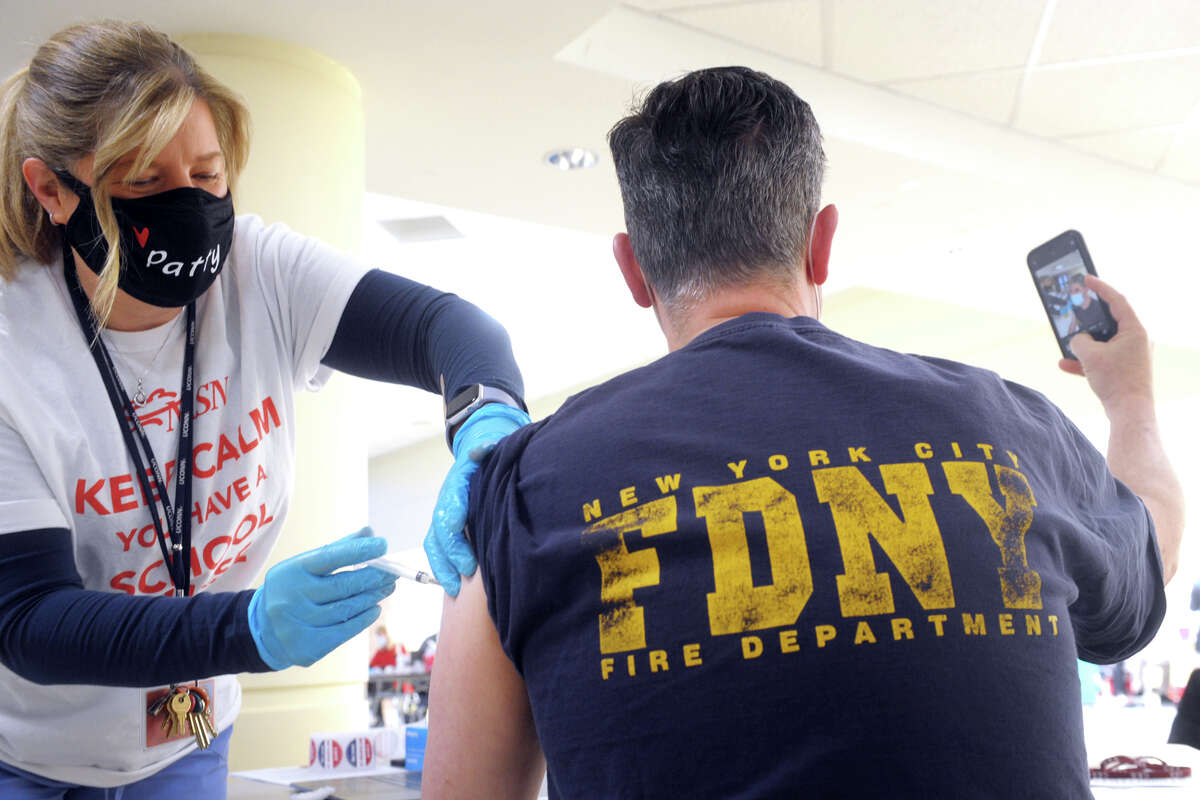 Andy Pohlen, a teacher from the Regional Center for the Arts, in Trumbull, takes a cellphone selfie as he receives a COVID-19 vaccination from school nurse Patty Gold during the vaccination clinic held for teachers and school staff in Trumbull, Conn. March 4, 2021.