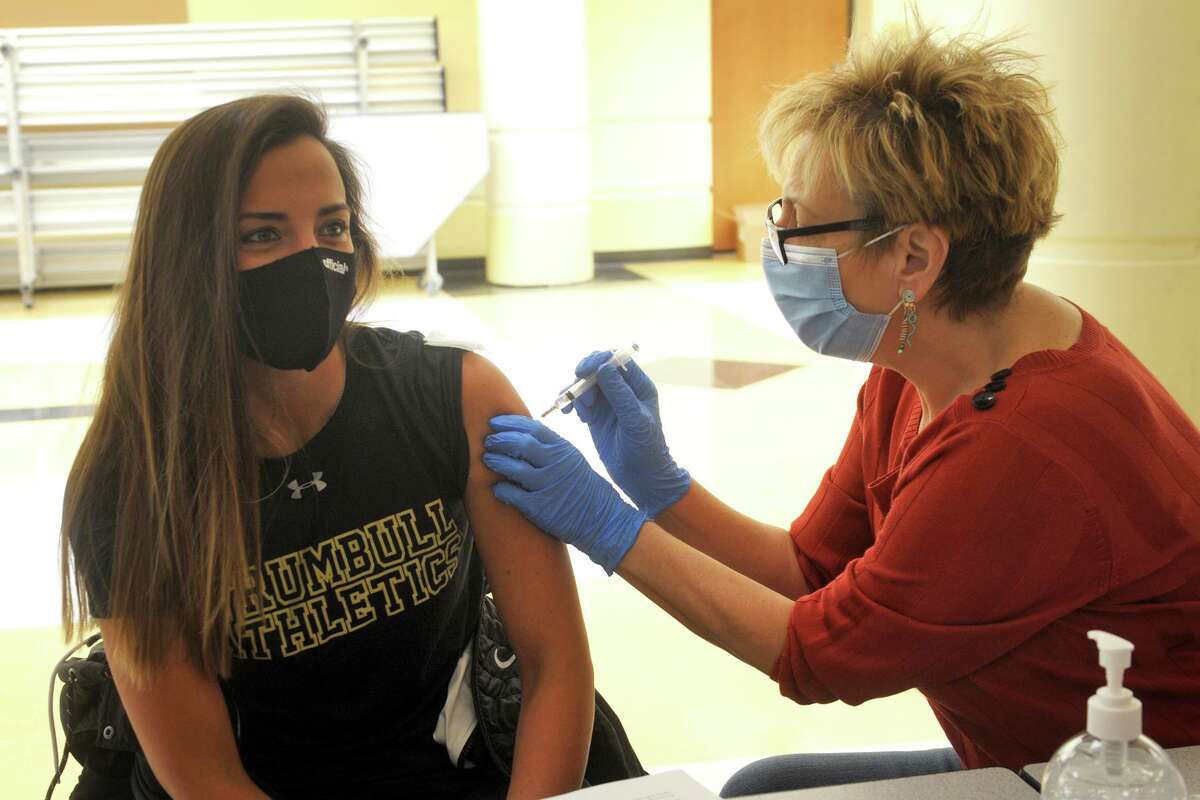 Jennifer Marrone, a health and physical education teacher at Trumbull High School, receives a COVID-19 vaccination from nurse Carol Pisani during the vaccination clinic held for teachers and school staff in Trumbull, Conn. March 4, 2021.