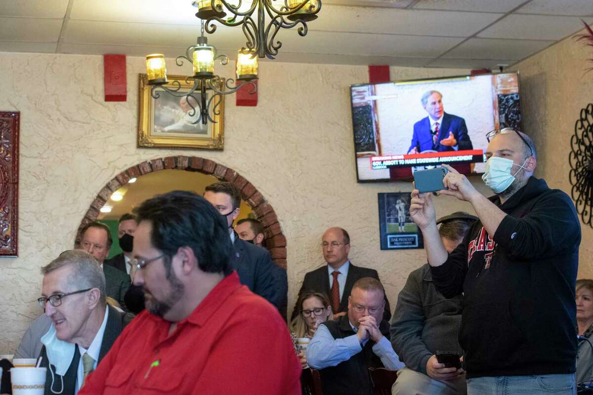 Texas Gov. Greg Abbott delivers an announcement, broadcasted on the TV in the background, as a crowd watches him make it at Montelongo's Mexican Restaurant on Tuesday, March 2, 2021, in Lubbock, Texas. Governor Abbott announced that he is rescinding executive orders that limit capacities for businesses and the statewide mask mandate. (Justin Rex/Lubbock Avalanche-Journal via AP)