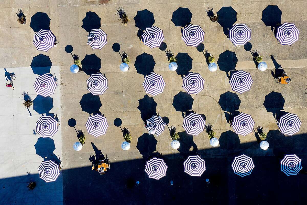 Umbrellas cover tables at an outdoor seating area behind the Ferry Building.