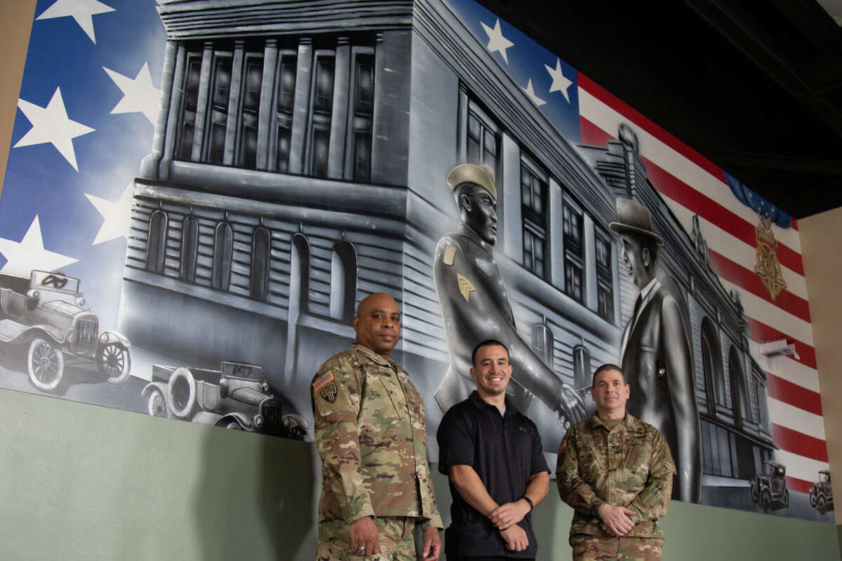 New York Army National Guard Command Sgt. Maj. Andrew H. Lampkins, the Command Sgt. Maj. of the 369th Sustainment Brigade and Col. Seth L. Morgulas, Commander of the 369th Sustainment Brigade pose with Christopher Rios, artist of the Sgt. Henry Johnson mural, at Camp Smith Training Site on February 26, 2021. The mural dedicated to Sgt. Henry Johnson, Medal of Honor recipient, who fought with the 369th Infantry in World War I, decorates the newly modernized Simulations Training Building at Camp Smith. (U.S. Army National Guard photo by Spc. Angela Minardi)