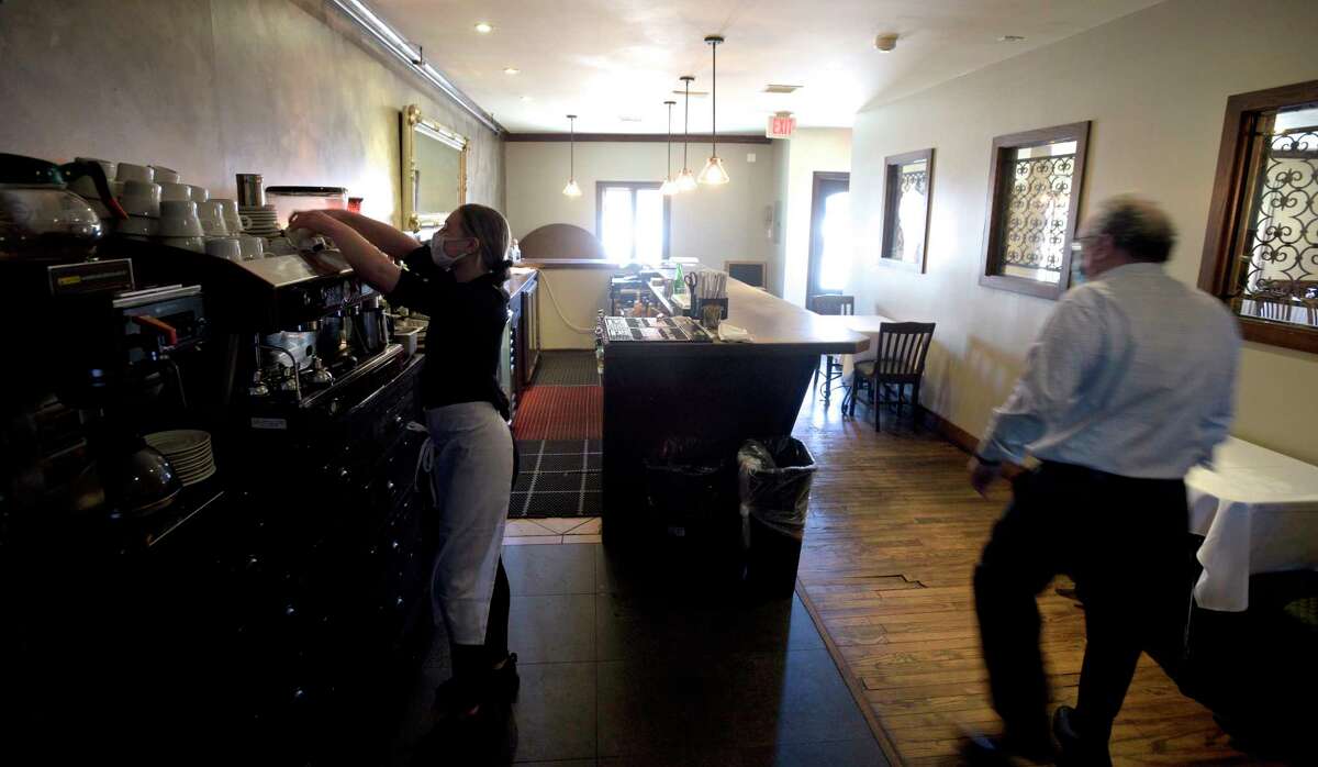 Lexi Hunt, server, organizes an espresso machine at the bar of La Zingara Ristorante as Roberto Moro, manager, walks by.. Because of COVID restrictions there is La Zingara has no seating at the bar. Governor Ned Lamont recently announced plans to ease those restrictions., Bethel, Conn. Friday, March 5. 2021.