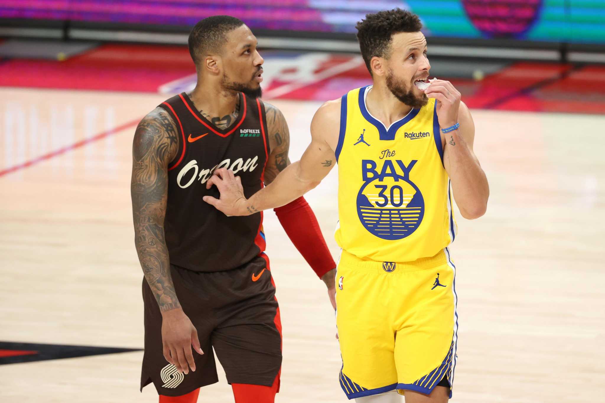 Golden State Warriors guard Stephen Curry (30) steps over Portland Trail  Blazers guard Damian Lillard (0) as he drives to the basket during the  first half of Game 3 of the NBA