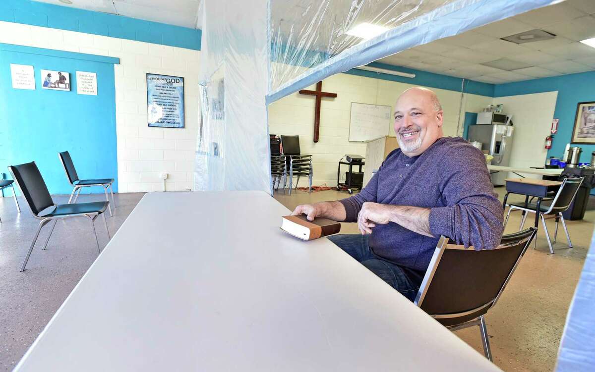 New Haven, Connecticut - Friday, March 5, 2021: Mike Caroleo, Pastor and Director of the 180 Center of New Haven ministry in New Haven on Grand Ave. that serves the homeless and people with difficult needs with discipleship programs dealing with conflict resolution, social work counseling, anger management and addiction issues, bible studies and church services and a sober house program, stands behind a Covid-19 barrier that splits the ministry building safely from visitors and men who are in the 180 Center program.