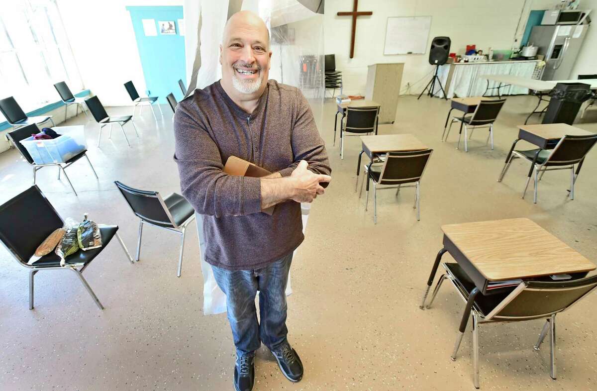 New Haven, Connecticut - Friday, March 5, 2021: Mike Caroleo, Pastor and Director of the 180 Center of New Haven ministry in New Haven on Grand Ave. that serves the homeless and people with difficult needs with discipleship programs dealing with conflict resolution, social work counseling, anger management and addiction issues, bible studies and church services and a sober house program, stands behind a Covid-19 barrier that splits the ministry building safely from visitors and men who are in the 180 Center program.