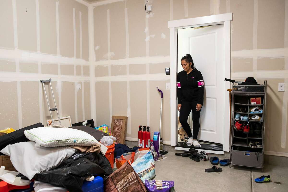 Bing Banaag looks at a pile of unpacked belongings in the garage of her home at the planned community at River Islands in Lathrop. The Banaag family moved from Hercules to Lathrop in February.