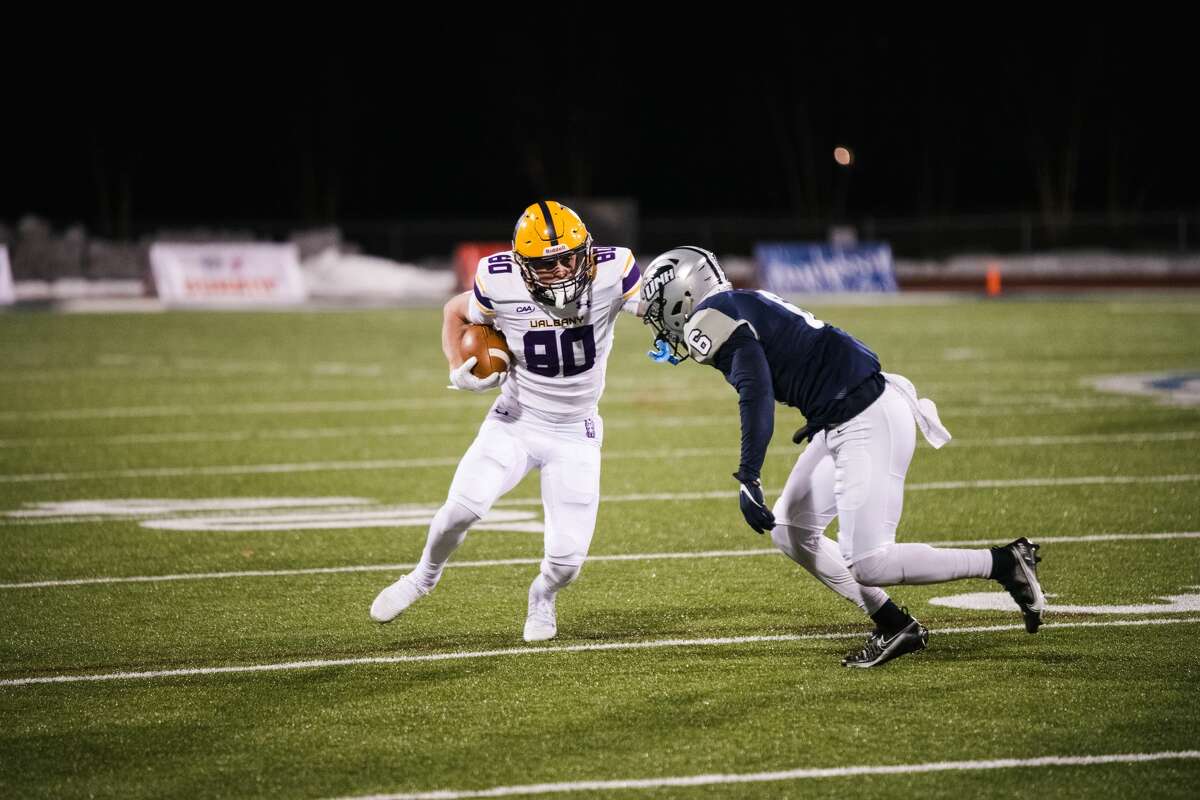 UAlbany redshirt freshman wide receiver Mike Gray looks to elude New Hampshire cornerback Derek Thompson in a Colonial Athletic Association football game Friday, March 5, 2021, in Durham, N.H. (China Wong/UNH athletics)
